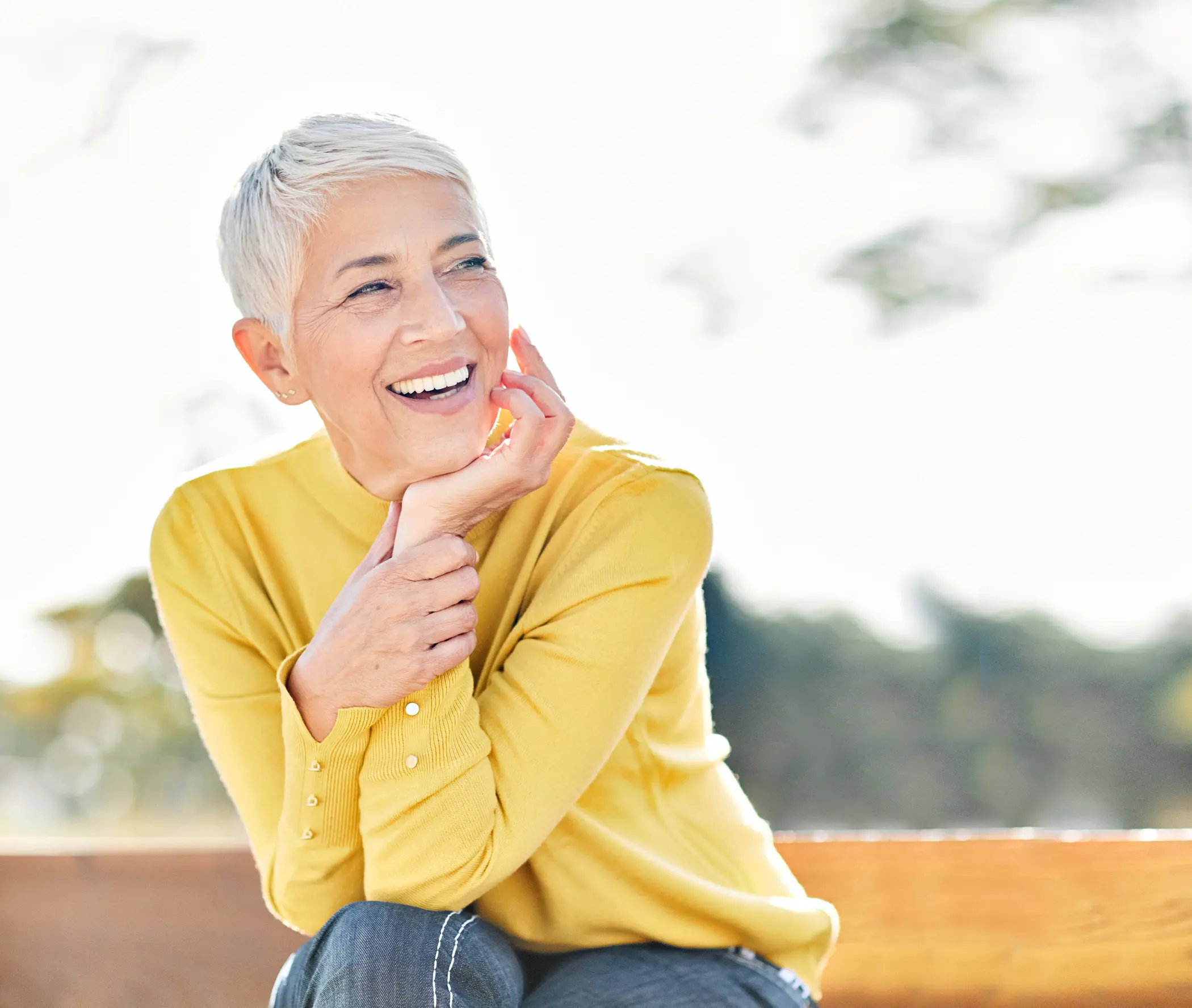 Medium-GettyImages-1770438730 Happy middle-aged woman with white hair sitting on a park bench
